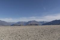 a desert area with rocks and a bike in the middle with mountains in the background