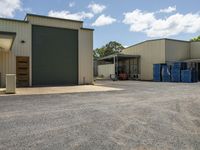 a large garage has two buildings and two trucks near by them to access the yard area