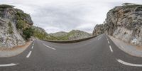 a mountain road passing over a canyon on a cloudy day in southern europe as seen from a view point perspective