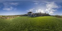 the grassy field is very large and green with clouds in the sky above it and a large house on top