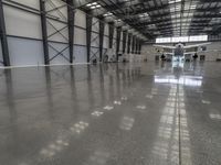 a large hangar with a plane in the corner, surrounded by windows and a wall