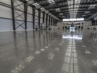 a large hangar with a plane in the corner, surrounded by windows and a wall