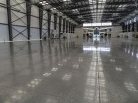 a large hangar with a plane in the corner, surrounded by windows and a wall