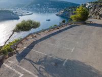 a paved parking lot with boats in the harbor at sunset near the cliff overlooking the sea