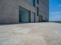 the gray concrete walls of a building have a line of steps on the left side