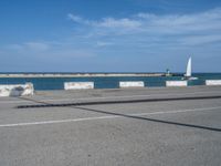 a sailboat is near some concrete blocks by the water and some sand beaching