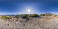 a fish eye lens shot of a dirt road and beach next to the ocean in spain