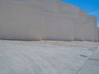 the gray concrete walls of a building have a line of steps on the left side