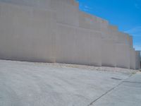 the gray concrete walls of a building have a line of steps on the left side