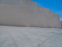 the gray concrete walls of a building have a line of steps on the left side