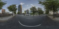 the view of an empty street looking down at a tall building with trees near it