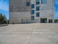 the gray concrete walls of a building have a line of steps on the left side