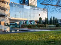 an open courtyard area has green grass, trees, and buildings on the other side