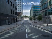 a empty road in a city area on a sunny day with some buildings and trees