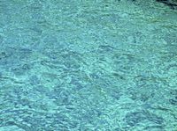 a blue ocean has a boat in the water and waves are moving around it in this photo