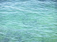 a blue ocean has a boat in the water and waves are moving around it in this photo
