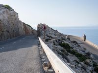 a cyclist is riding on a steep hill road overlooking the ocean and some rocks,