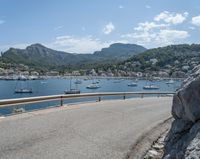 a paved road beside some large boats and a bridge with a bridge to the water