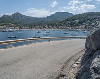 a paved road beside some large boats and a bridge with a bridge to the water