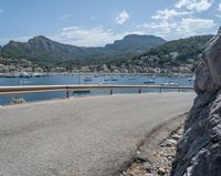 a paved road beside some large boats and a bridge with a bridge to the water