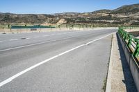 an empty street with many mountains in the background with white painted lines in the center