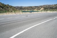 an empty street with many mountains in the background with white painted lines in the center