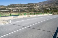 an empty street with many mountains in the background with white painted lines in the center