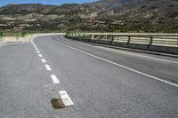 the empty road in front of a large mountainside area has been deserted and not yet to be used