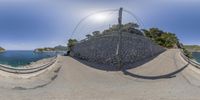 a fish eye view of a road at the beach with mountains in the background and trees around