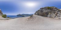 a mountaintop view with road curves along the beach and water at the top of it