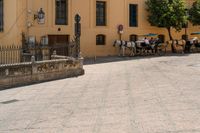 a large brick area has several benches and tables with people sitting in the background on a sunny day