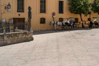 a large brick area has several benches and tables with people sitting in the background on a sunny day