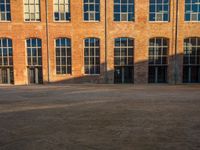 a woman walking her dog in front of a building with tall windows and brick walls