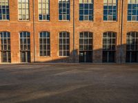 a woman walking her dog in front of a building with tall windows and brick walls