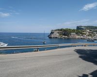 a paved road beside some large boats and a bridge with a bridge to the water