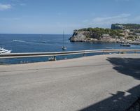 a paved road beside some large boats and a bridge with a bridge to the water
