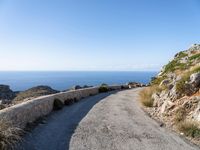 the curve road leads to an ocean view from a high cliff side overlook at rocky coastline and blue water