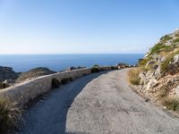 the curve road leads to an ocean view from a high cliff side overlook at rocky coastline and blue water