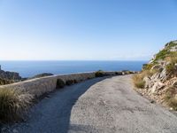 the curve road leads to an ocean view from a high cliff side overlook at rocky coastline and blue water