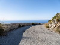 the curve road leads to an ocean view from a high cliff side overlook at rocky coastline and blue water