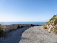 the curve road leads to an ocean view from a high cliff side overlook at rocky coastline and blue water