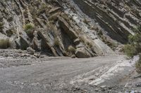 a mountain road is lined with rocky boulders on the side of it and a person walking across the side