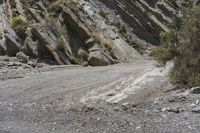 a mountain road is lined with rocky boulders on the side of it and a person walking across the side