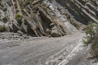 a mountain road is lined with rocky boulders on the side of it and a person walking across the side