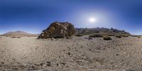 a lone rock in the desert at sun rise on the horizon with a clear sky