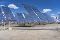 an array of solar panels in a desert field with a flag sign in the middle