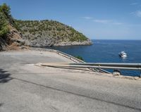 a paved road beside some large boats and a bridge with a bridge to the water