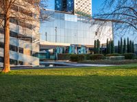 a building with large glass windows sits on a park in the background of a grassy area