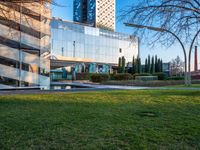 a building with large glass windows sits on a park in the background of a grassy area