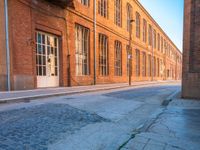 an empty side walk lined with buildings on a sunny day of the day with sunlight in it